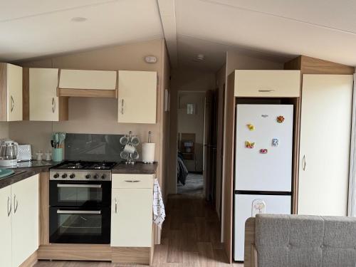 a kitchen with white cabinets and a refrigerator at Andreas Riverside Retreat at 7 Lakes Country Park in Crowle
