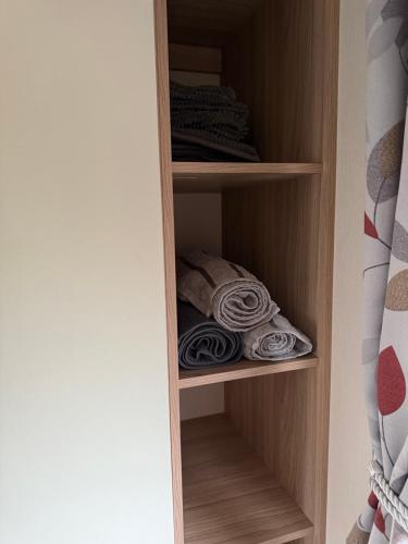 a closet with wooden shelves with folded towels at Andreas Riverside Retreat at 7 Lakes Country Park in Crowle