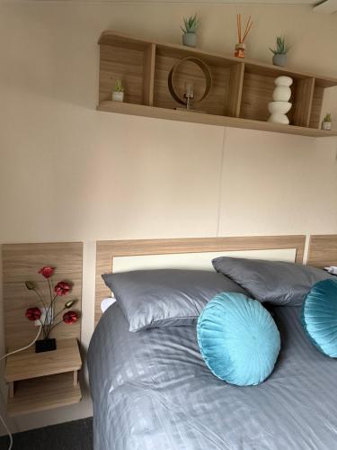 a bedroom with a bed with blue pillows on it at Andreas Riverside Retreat at 7 Lakes Country Park in Crowle