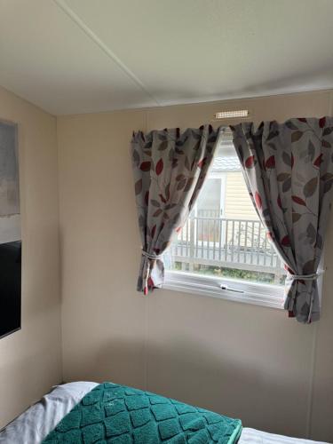 a bedroom with a bed and a window with curtains at Andreas Riverside Retreat at 7 Lakes Country Park in Crowle
