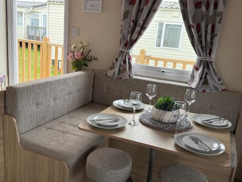 a table with plates and wine glasses on a couch at Andreas Riverside Retreat at 7 Lakes Country Park in Crowle