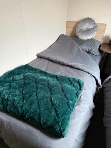 a bed with a green quilt on top of it at Andreas Riverside Retreat at 7 Lakes Country Park in Crowle