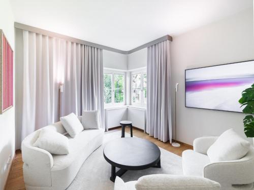 a living room with white furniture and a flat screen tv at Stadtchalet Forsthaus in Kitzbühel