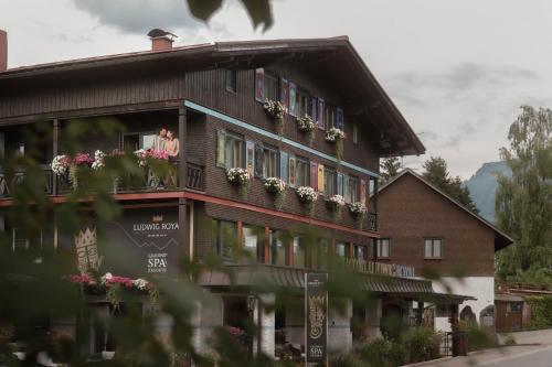 a woman is looking out the window of a building at Alpin & Wellness Resort Ludwig Royal in Oberstaufen