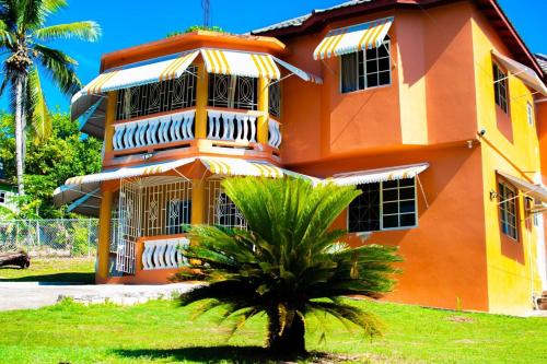 an orange building with a palm tree in front of it at Yaad Vibes Getaway in Santa Cruz