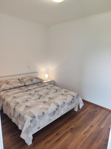a white bedroom with a bed and a wooden floor at Apartments Marija in Trogir