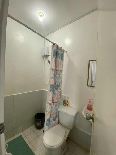 a bathroom with a toilet and a shower curtain at Eevee's Homes B14 L19 Bacolod in Bacolod