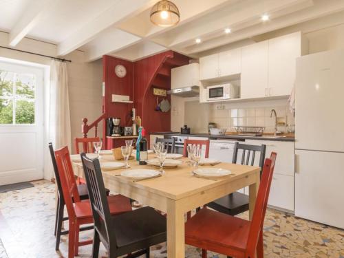 a kitchen with a wooden table with chairs and a refrigerator at Voici un titre accrocheur et concis pour l'annonce : **"Charmante longère bretonne avec grand jardin privatif, proche plages et sites touristiques"** - FR-1-306-841 in Donges