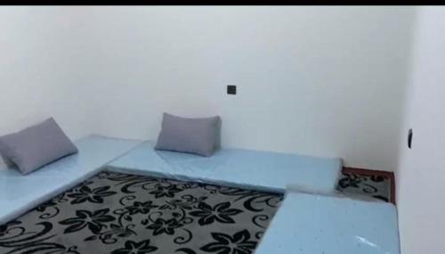 a bed with two pillows and a rug in a room at منتزه السلامة Parc ASSALAMA in Kenitra