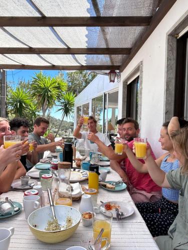 a group of people sitting around a table drinking orange juice at Moby Dick Lodge Cascais in Cascais