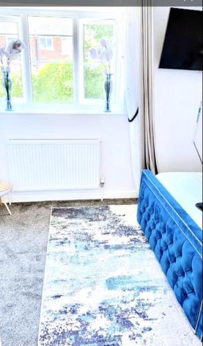 een blauwe bank in een kamer met een raam bij Hotel Feel, Home Comfort in Manchester