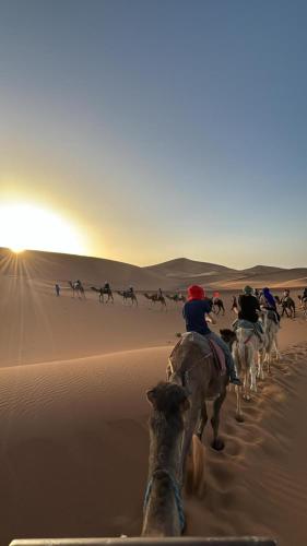 a group of people riding horses in the desert at Touareg Desert Camp Erg Chigaga in El Gouera