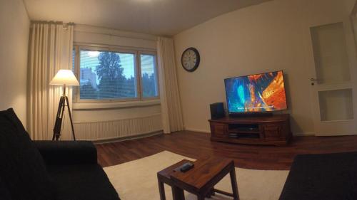 sala de estar con TV de pantalla plana y mesa en City Apartment Sairaalakatu, en Kuopio