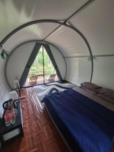 a bedroom with a bed in a tent at Tepian Pinus Glamping in Palayangan