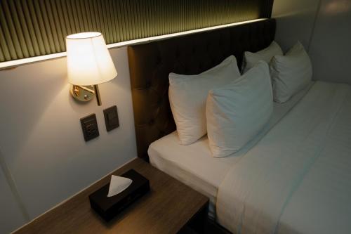 a bed with white pillows and a table with a lamp at THE TIMES HOTEL in Angeles