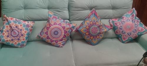 four pillows sitting on top of a couch at Charmosa Casa de Madeira a 700 metros da praia in Rio das Ostras