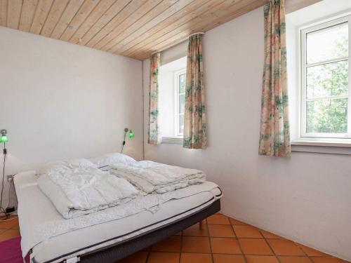 a bed in a room with two windows at Luxury Retreat with Pool - By Traum Ferienwohnungen in Thyholm