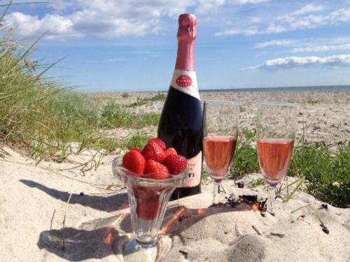 a bottle of wine with a bowl of strawberries and two glasses at Luxury Retreat with Spa - By Traum Ferienwohnungen in Dannemare