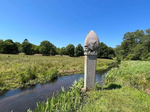 a stone monument in a field next to a river at 5 star holiday home in Hovborg-By Traum in Hovborg