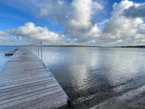 a wooden dock with a boat on the water at 4 person holiday home on a holiday park in Lemvig in Lemvig