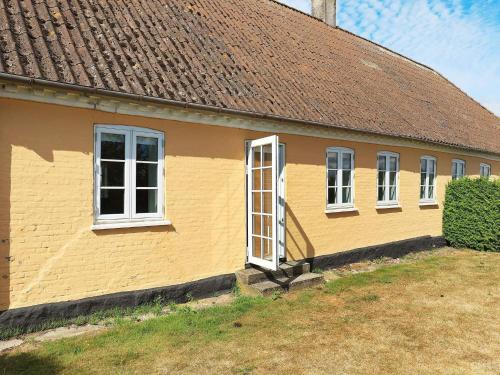 a yellow house with white windows and a brown roof at 7 person holiday home in Faaborg-By Traum in Fåborg