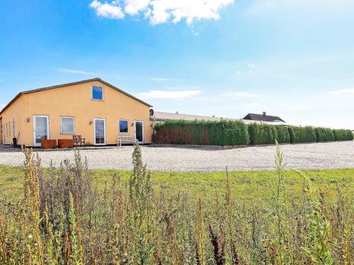 a yellow building in a field next to a field at 6 person holiday home in Faaborg-By Traum in Fåborg