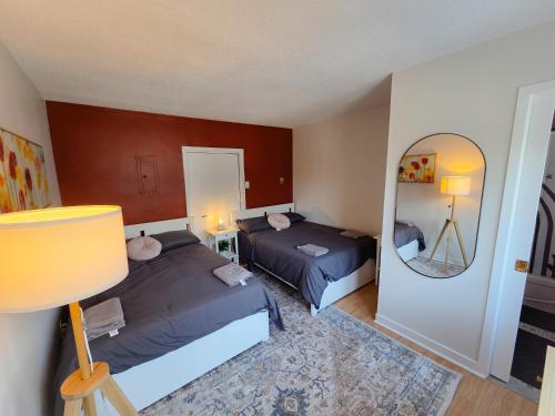 a bedroom with two beds and a mirror at Sandy Hill Downtown Guesthouse in Ottawa