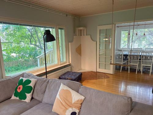 un soggiorno con divano grigio e ampie finestre di Natural Cottage a Kauniainen