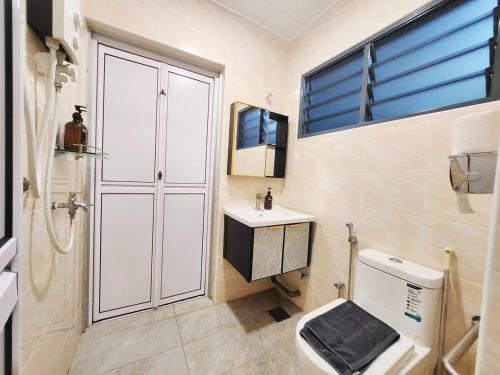 a bathroom with a toilet and a sink and a window at Ipoh pasir puteh vibrant home 4br 15 pax in Ipoh