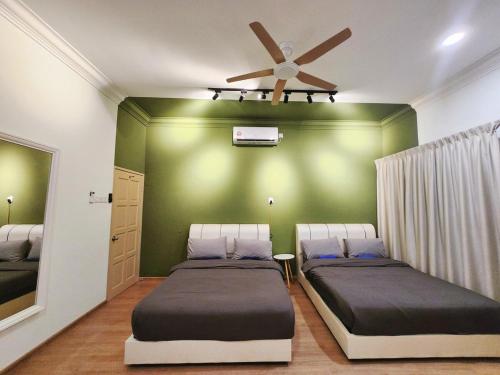 a bedroom with two beds and a ceiling fan at Ipoh pasir puteh vibrant home 4br 15 pax in Ipoh