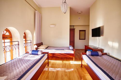 a room with two beds and a flat screen tv at Centrum Obsługi Turysty Kordegarda in Raczki