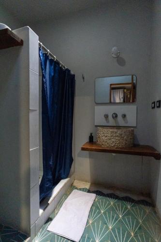 a bathroom with a blue shower curtain and a mirror at Maui Hostels Tulum in Tulum