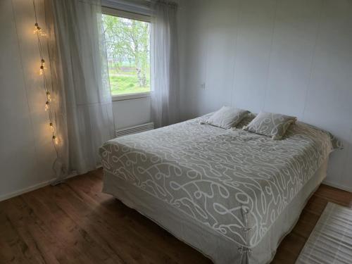 a bedroom with a white bed with a window at Small cottage in Toholampi