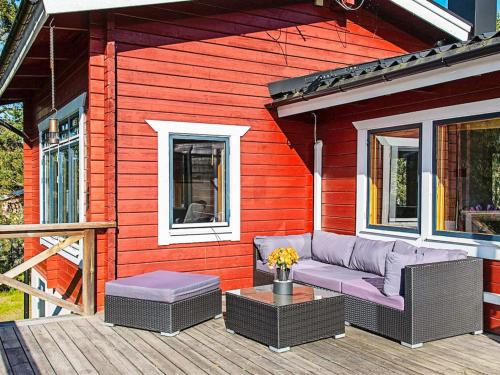 a red house with a couch and a table on a deck at 7 person holiday home in VÄRMDÖ-By Traum in Värmdö