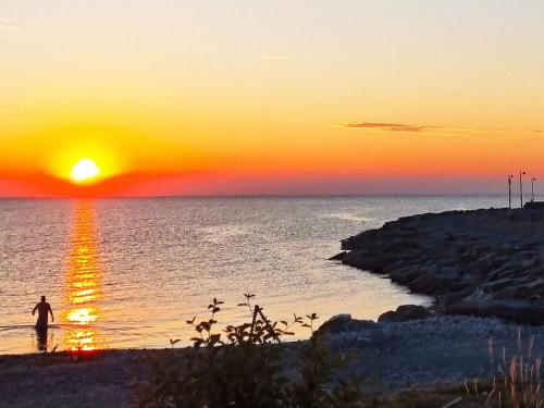 a person walking on the beach at sunset at 3 person holiday home in LÖTTORP-By Traum in Löttorp