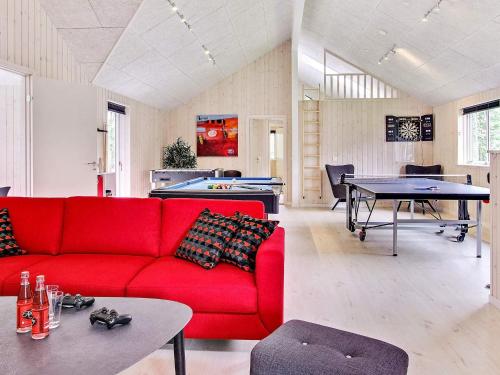 a living room with a red couch and a pool table at 20 person holiday home in Hasselberg in Kappeln