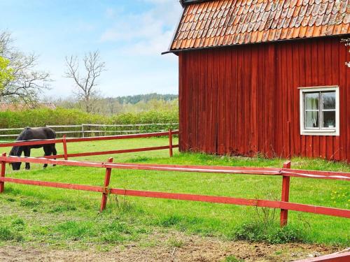 a horse grazing in a field next to a red barn at 5 person holiday home in FLEN-By Traum in Flen