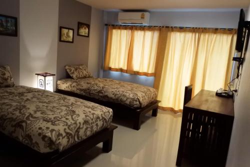 a bedroom with two beds and a desk and curtains at Old City Boutique House in Sukhothai