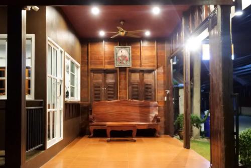 a porch with a wooden bench and a ceiling fan at Old City Boutique House in Sukhothai