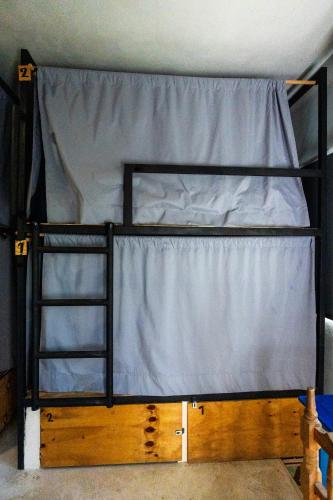 a bunk bed with a curtain on top of it at Maui Hostels Tulum in Tulum