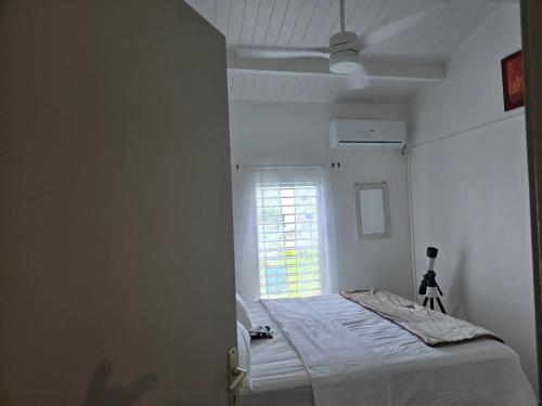 a white room with a bed and a window at Maison confortable à Baie-Mahault avec jardin privatif in Baie-Mahault