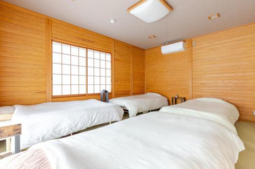 three beds in a room with wooden walls at 一棟貸切別荘 神氣龍 in Sagamihara