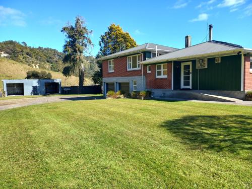 a house with a large lawn in front of it at Hill top view farm stay in Uruti