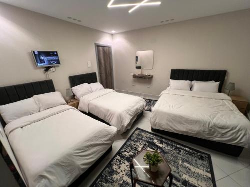 a room with three beds and a tv on the wall at Karnak Pyramids View inn in Cairo