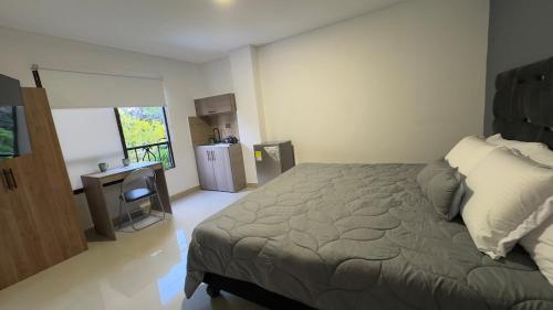 1 dormitorio con cama, escritorio y nevera en Venezia 208, en Cali