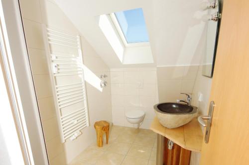 ein Bad mit einem Waschbecken und einem WC mit einem Dachfenster in der Unterkunft Villa am Schwanenteich in Spremberg
