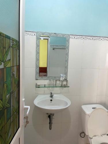 a bathroom with a sink and a toilet and a mirror at Hanh Thông Homestay in Dong Hoi