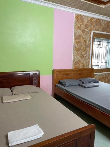 two beds in a room with green and pink at Hanh Thông Homestay in Dong Hoi