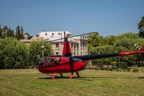a small red helicopter sitting in a field at Senador Dupont- Convento San Francisco & Arboles in Tigre