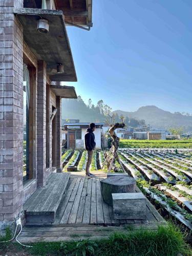 two people standing on a wooden deck next to a building at Eco Wooden Farmhouse in Dieng
